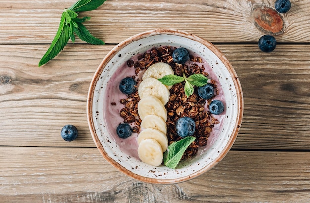 Tigela de smoothie de banana com mirtilos de granola de chocolate e comida saudável de menta