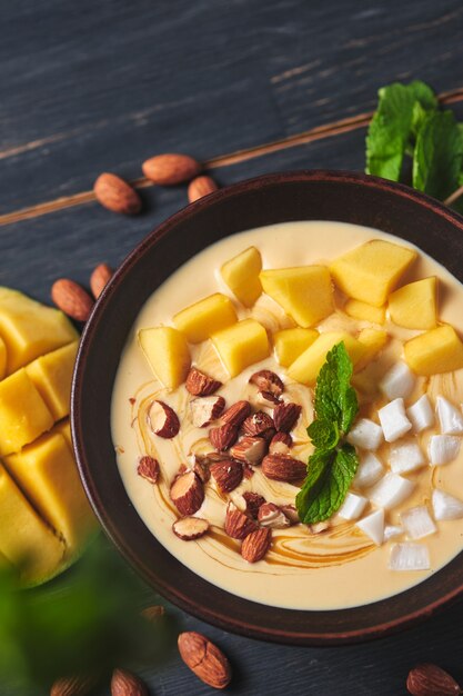 Tigela de smoothie tropical com banana, manga, coco e nozes