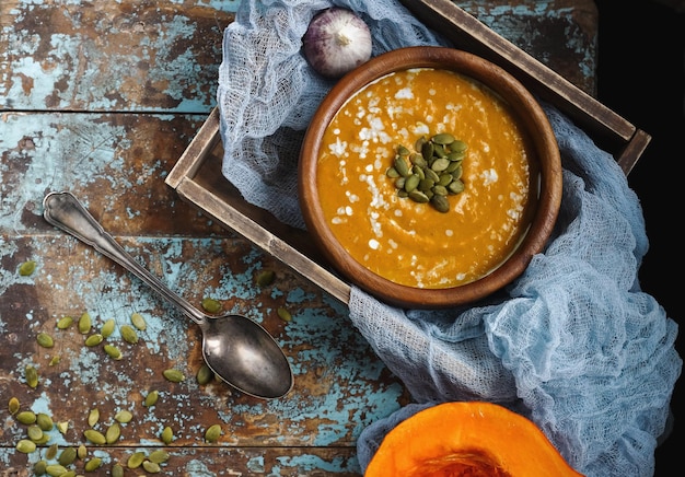 Tigela de sopa de abóbora caseira tradicional com creme de sementes e pão na mesa de madeira rústica alimentação saudável outono colheita vista superior foco seletivo