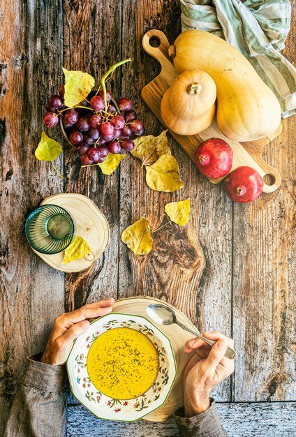 Tigela de sopa de abóbora quente nas mãos Segurando uma tigela de sopa de abóbora vegana Comida de conforto Foco seletivo