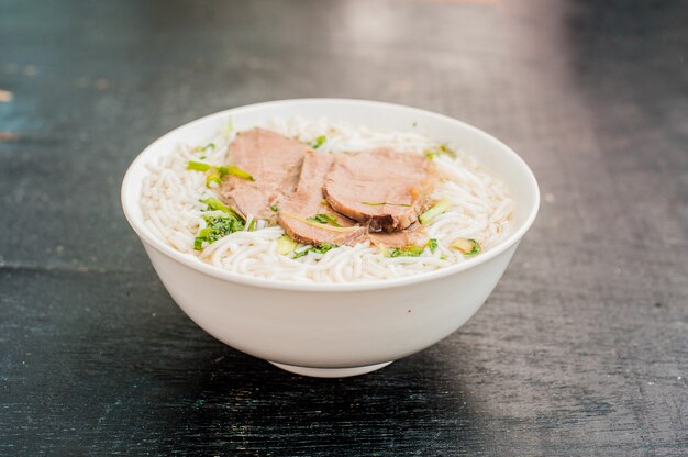 Tigela de sopa de carne tradicional vietnamita pho bo no fundo escuro de madeira velho