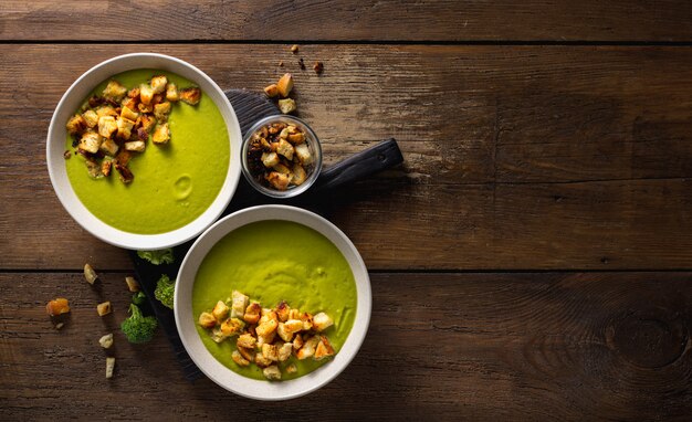 Tigela de sopa de creme de brócolis com croutons de pão em um fundo de madeira