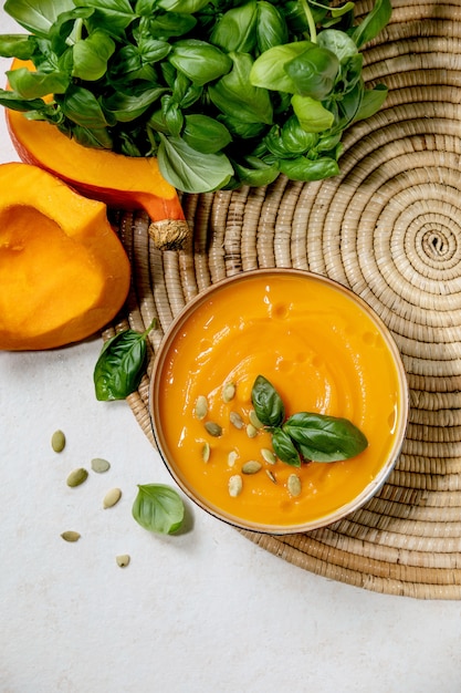 Tigela de sopa de creme vegetariana de abóbora ou cenoura decorada com manjericão fresco