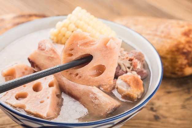 Foto tigela de sopa de raiz de lótus de osso de porco em uma mesa de madeira