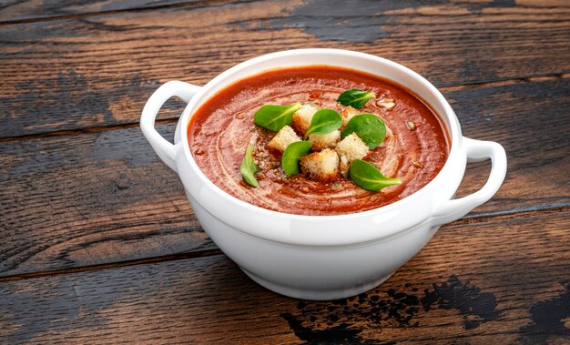 Tigela de sopa de tomate na mesa de madeira com espaço de cópia