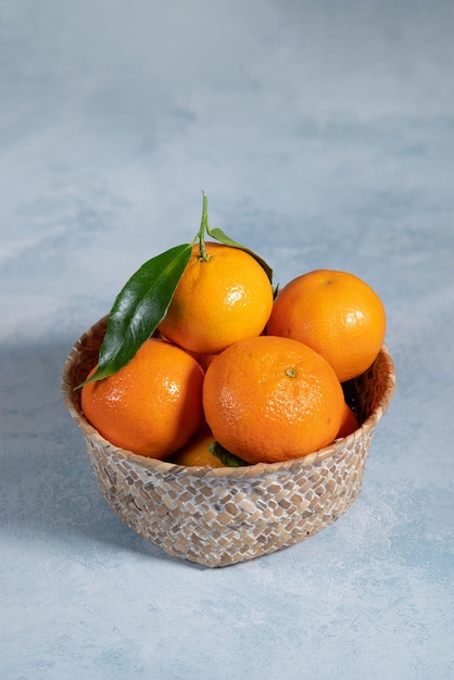 Tigela de tangerinas frescas em fundo azul, tiro vertical