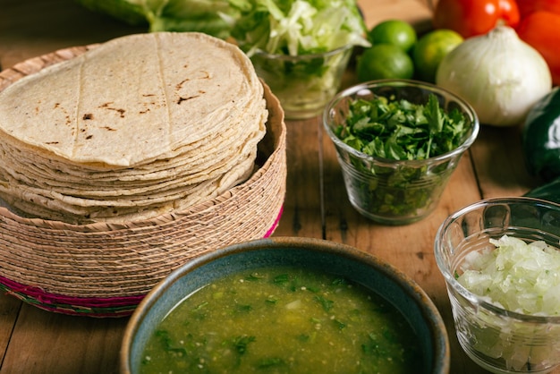 Tigela de tortilhas com molho verde e legumes em uma mesa de madeira Comida mexicana típica