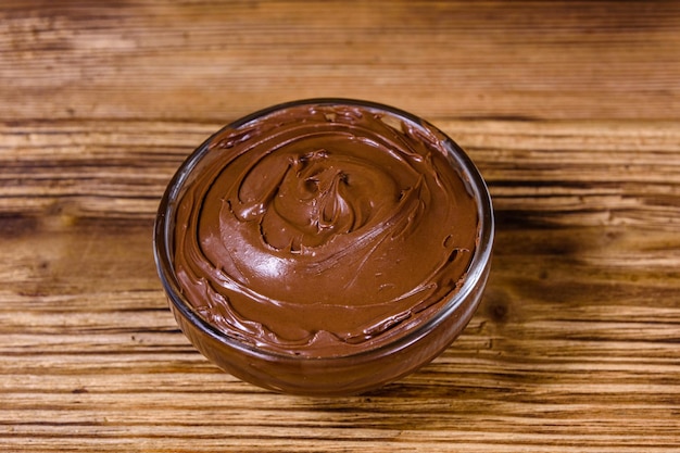 Foto tigela de vidro com chocolate espalhado em uma mesa de madeira