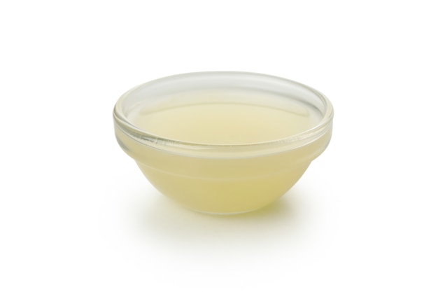Tigela de vidro com suco de limão isolada no fundo branco