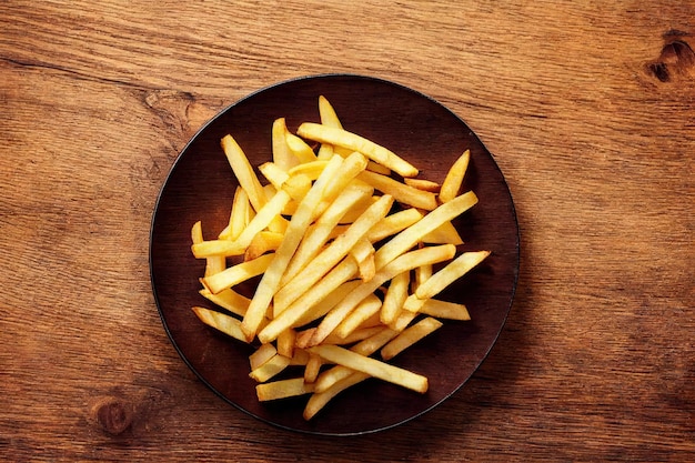 Tigela marrom cheia de batatas fritas douradas na mesa de madeira clara