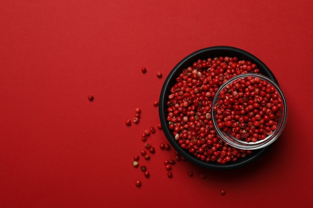 Tigela preta de grãos de pimenta vermelha em fundo vermelho