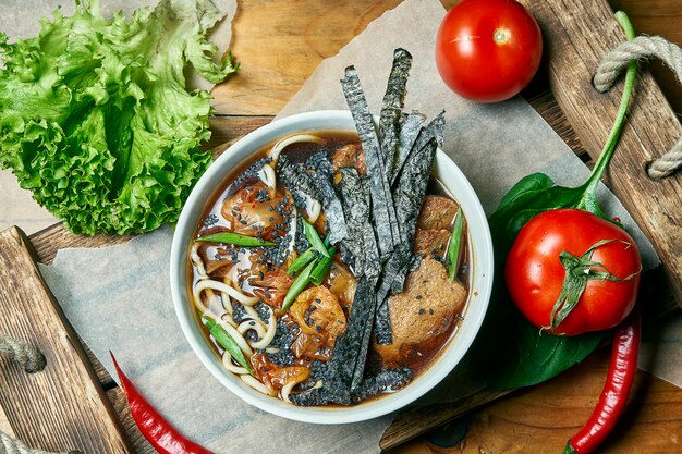 Tigela vegetariana com sopa de ramen, cogumelos shiitake, carne de soja em uma bandeja de madeira em uma composição com legumes frescos. comida saudável.