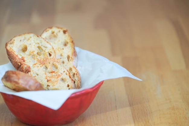 Tigela vermelha com ciabatta italiana de pão frito de ovo com grandes buracos na superfície de madeira, café da manhã fresco