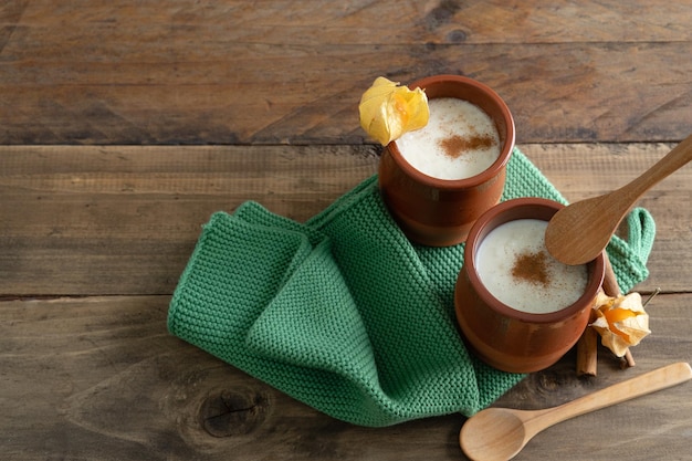 Tigelas cerâmicas de arroz doce e canela com decoração em fundo de madeira com colheres e guardanapo de pano. Copie o espaço.