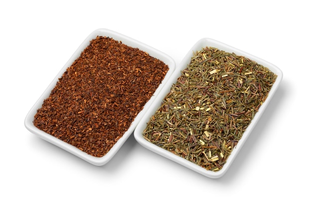 Tigelas com chá de rooibos secos, chá vermelho e folhas de chá verde de rooibos sobre fundo branco