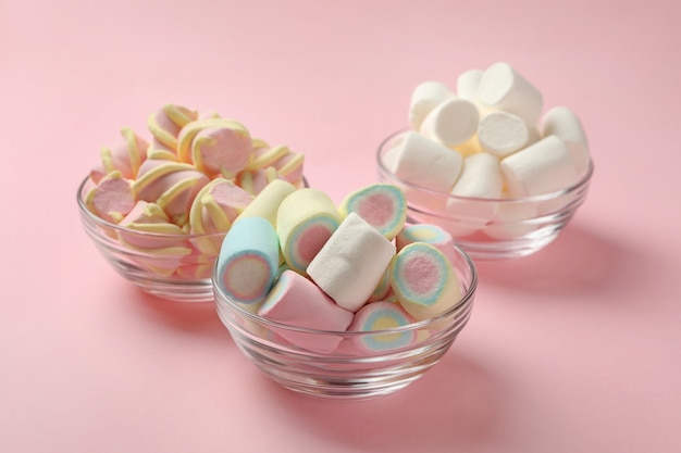 Tigelas com marshmallows em fundo rosa