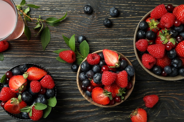 Tigelas com mistura de frutas vermelhas e suco em madeira