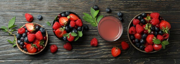 Tigelas com mistura de frutas vermelhas e suco em madeira