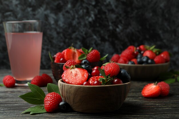 Tigelas com mistura de frutas vermelhas e suco na mesa de madeira