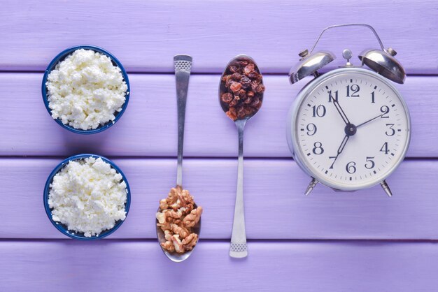 Foto tigelas com queijo cottage, colheres com nozes e passas