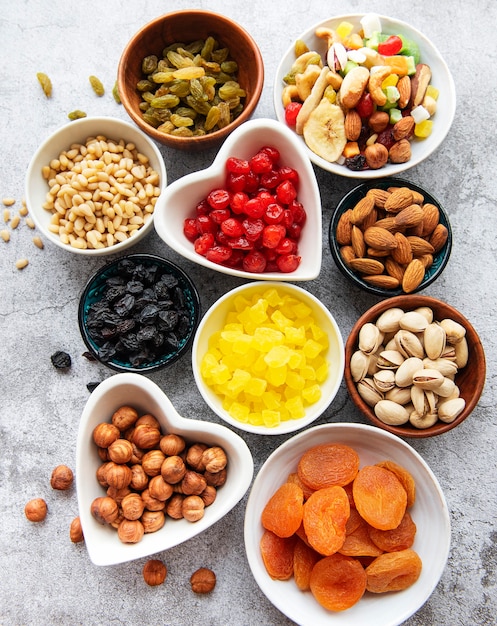 Tigelas com várias frutas secas e nozes em uma superfície de concreto cinza