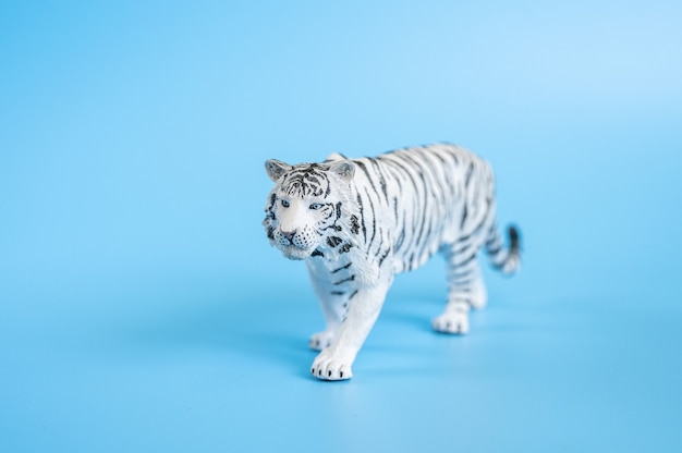 El tigre, símbolo del año 2022. Figura de juguete de plástico blanco tigre sobre un fondo azul.