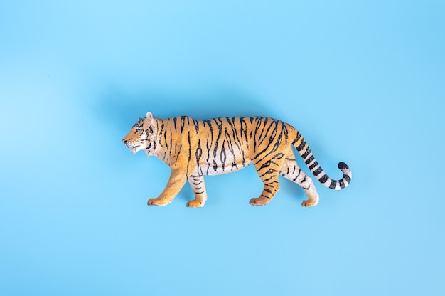 El tigre, símbolo del año 2022. Figura de juguete de plástico naranja tigre sobre un fondo azul. vista superior