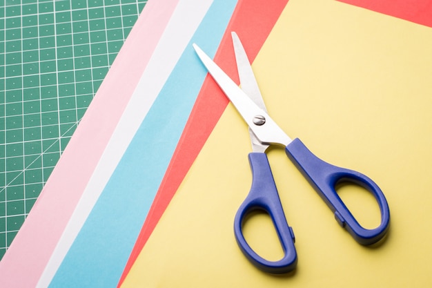 Tijeras azules sobre papeles de diferente color para hacer origami