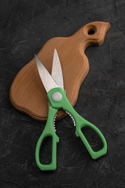 Tijeras de cocina afiladas en una tabla de cortar de madera en la cocina