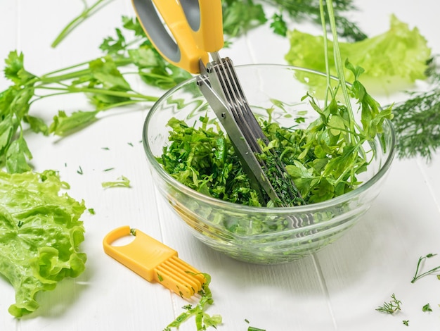 Tijeras de cocina amarillas y herramientas de limpieza con una ensaladera El proceso de preparación de un plato vegetariano