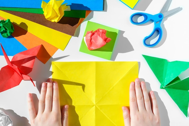 Tijeras para manualidades con papel papel de color sobre mesa blanca Origami Lugar de trabajo para niños Preescolar
