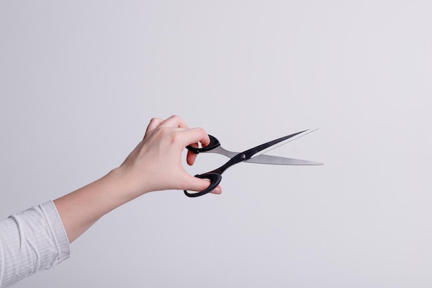 Tijeras de papelería en la mano de una niña sobre un fondo blanco. foto de alta calidad