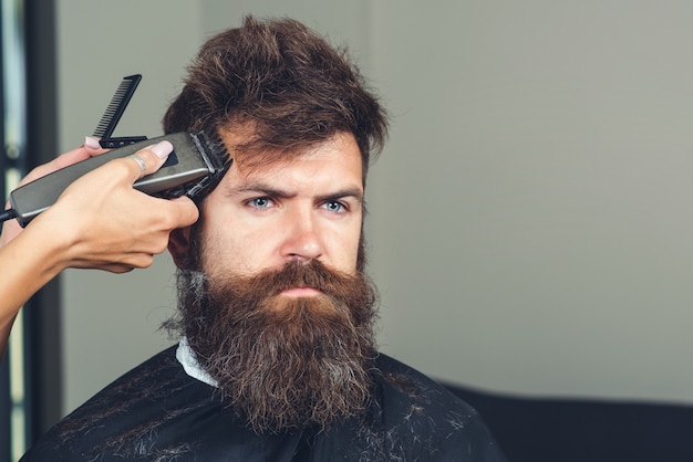 Tijeras de peluquero. Hombre en peluquería. Hipster, hombre brutal. Navaja de afeitar, peluquería, barba. Corte de pelo para hombre. Hombre barbudo, barba exuberante, guapo. Peluquería. Navaja de afeitar vintage. Concepto de peluquería.