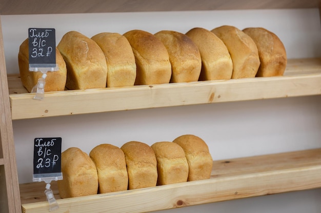 Tijolos de pão de trigo estão em prateleiras de madeira na loja Deliciosos pães de pão na padaria