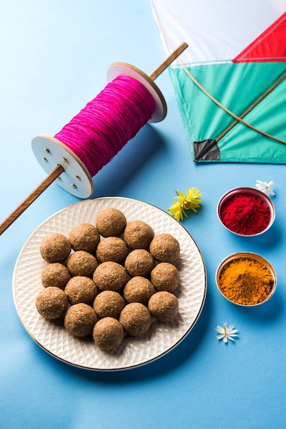 Til Gul O Sweet Sesame Laddu con Fikri y Kite con haldi Kumkum para el festival Makar Sankranti sobre fondo cambiante, enfoque selectivo