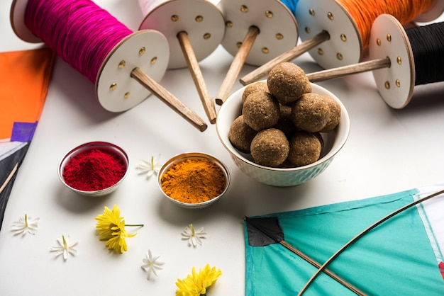 Til Gul OU Sweet Sesame Laddu com Fikri e Kite com haldi Kumkum para o festival Makar Sankranti sobre fundo sombrio, foco seletivo