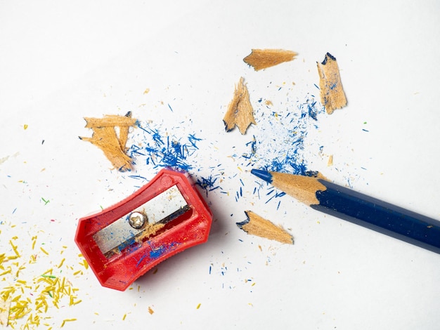 Útiles escolares Afilado de lápices Lápices multicolores sobre un fondo blanco Virutas de madera El proceso de preparación para el trabajo Desorden creativo