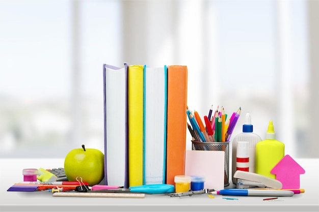 Útiles escolares coloridos y libros sobre fondo claro