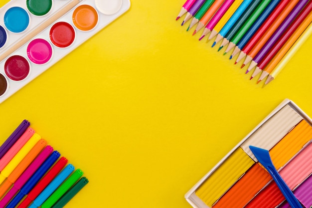 Útiles escolares coloridos sobre un fondo amarillo