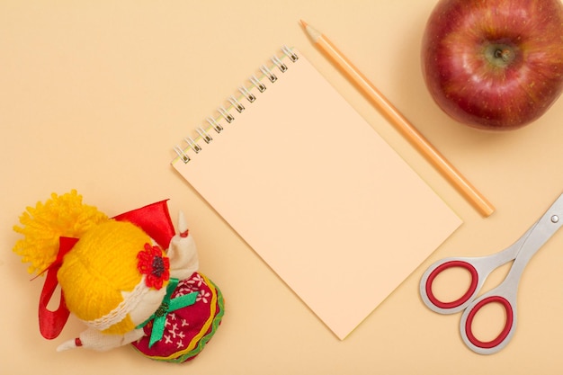 Útiles escolares Cuaderno color lápiz tijeras manzana y muñeca sobre fondo beige