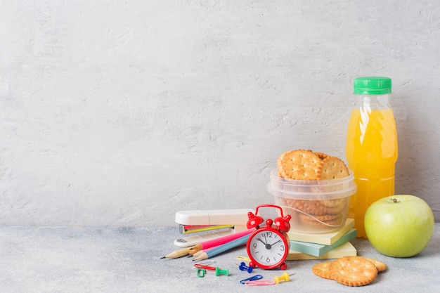 Útiles escolares y galletas de desayuno, zumo de naranja y manzana fresca.