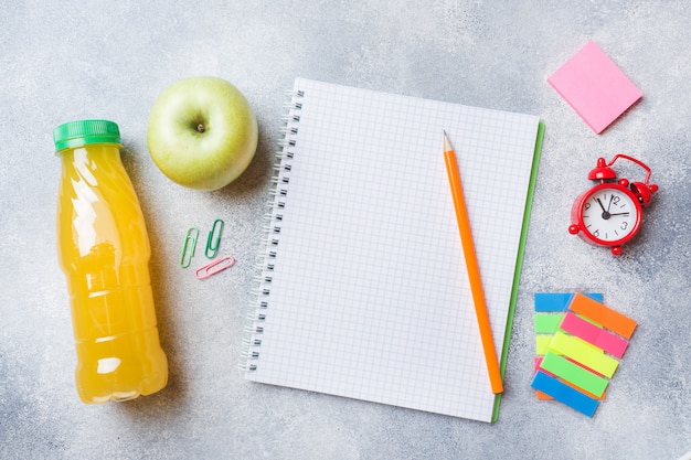 Útiles escolares y galletas de desayuno, zumo de naranja y manzana fresca.