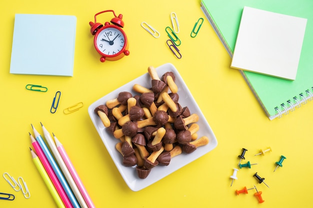 Útiles escolares y galletas para una merienda en la mesa amarilla con espacio de copia. escuela de concepto