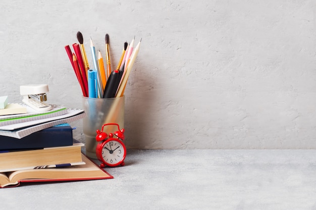 Útiles escolares, libros, cuadernos, lápices en gris con copia espacio.