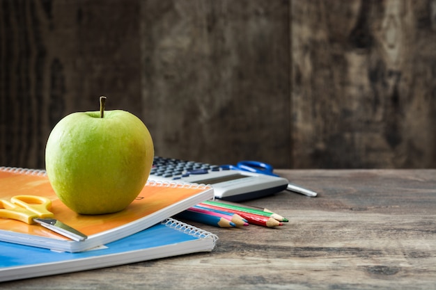 Útiles escolares y manzana verde sobre madera, concepto de regreso a la escuela