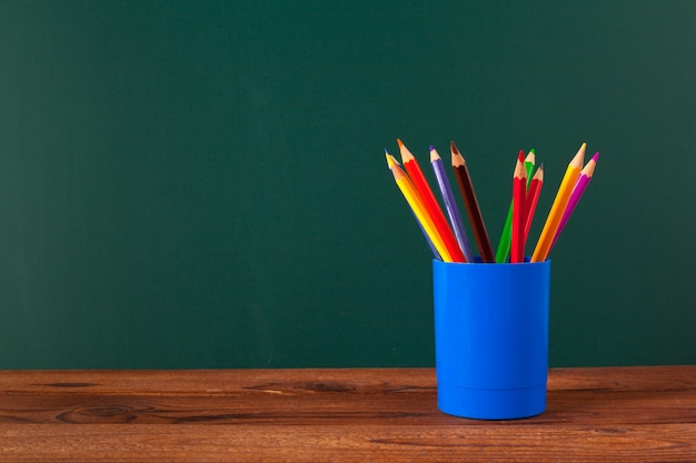 Útiles escolares en una mesa de madera y fondo de pizarra