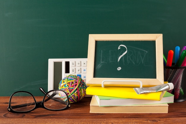 Útiles escolares en una mesa de madera y pizarra