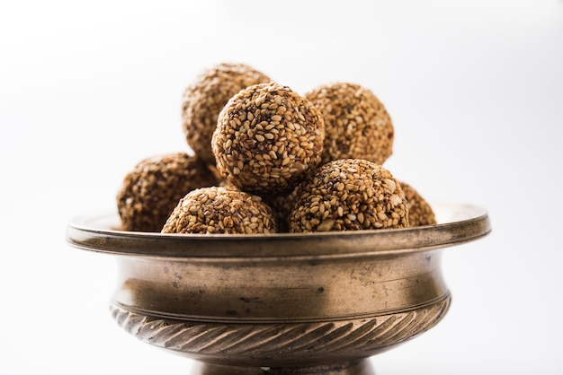 Tilgul Laddu oder Til Gul Kugeln für Makar Sankranti, es ist ein gesundes Essen aus Sesam, zerstoßenen Erdnüssen und Jaggery. in einer Schüssel serviert. selektiver Fokus mit Details.