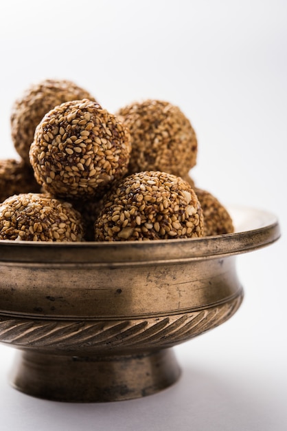 Tilgul Laddu oder Til Gul Kugeln für Makar Sankranti, es ist ein gesundes Essen aus Sesam, zerstoßenen Erdnüssen und Jaggery. in einer Schüssel serviert. selektiver Fokus mit Details.