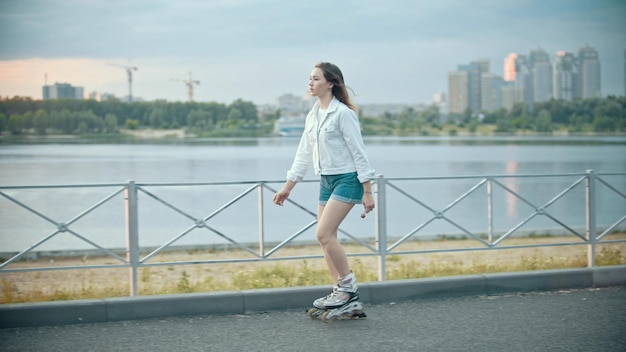 Una tímida adolescente patinando en el paseo marítimo de día